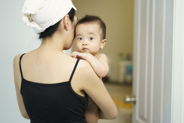 亚洲妈妈抱着她可爱的小婴儿在卧室洗澡。儿童护理常规。家庭生活。母亲和婴儿。图片下载