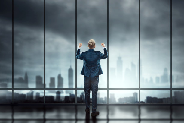 穿着商务西装的商人站在大窗户前眺望城市图片下载