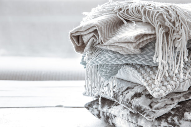 靠近一堆舒适的斯堪的纳维亚风格的毯子和枕头。图片下载