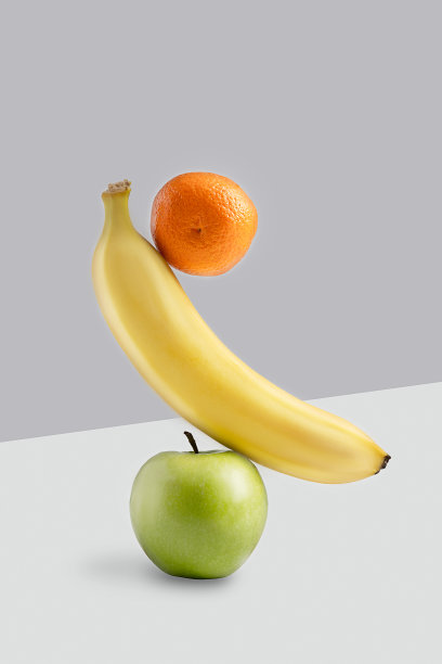 在白色和灰色的现代背景下，平衡的悬浮香蕉，橘子和苹果组图片下载
