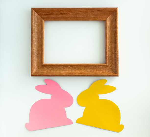 用黄色、粉色的小兔子和木制框架组成的复活节作品。前视图。本空间图片下载