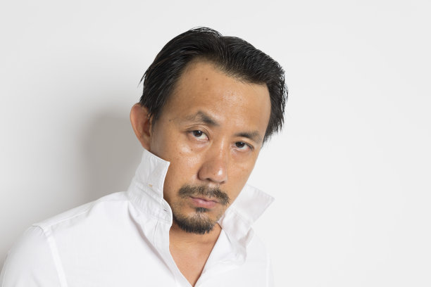 中年亚洲人严肃地看着相机在白色的背景。图片下载