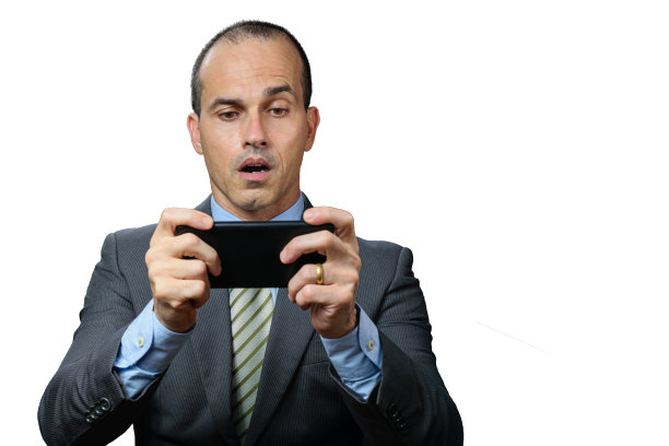 一个穿西装打领带的成熟男人，一边玩着智能手机，一边露出惊讶的表情。图片下载