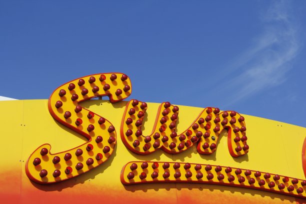 清澈的蓝天和红色的发光标志，用大写字母拼写出单词SUN图片下载