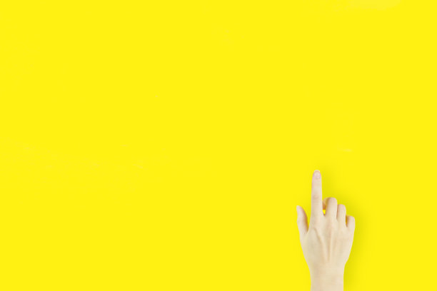 年轻女子的食指指向黄色背景上的手图片下载