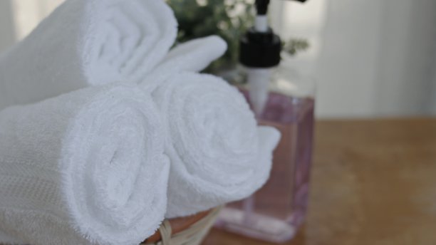 毛巾放在篮子上，白色的桌面，一瓶液体肥皂，浴室洗澡的水疗设备，复印空间，图片下载