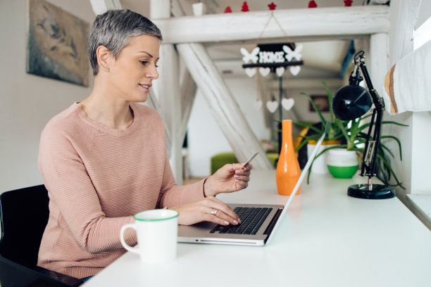 一个女人在家庭办公室网上购物的照片图片下载