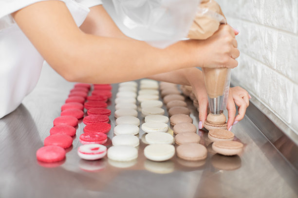 马卡龙的制造，一步一步的流程。近距离图片的女性巧克力甘纳许坐在巧克力马卡龙壳上。图片下载