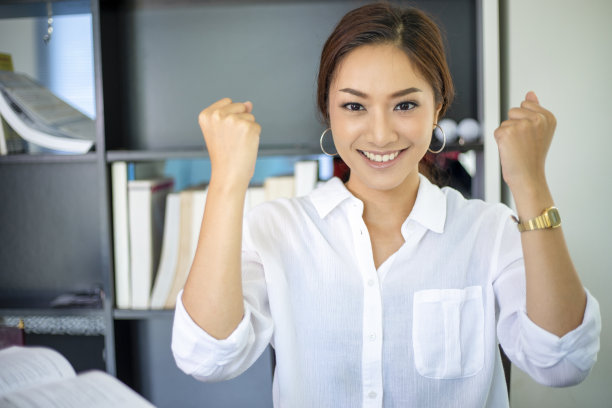 美丽的亚洲女学生在家里看书和用笔记本工作。她是快乐和成功的图片下载