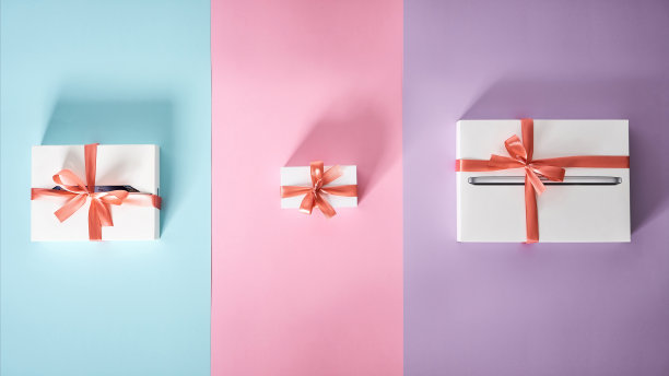 一套不同大小的白色礼盒，彩色背景，红色蝴蝶结图片下载