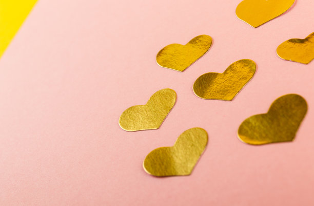 闪亮的金色心形贴纸在粉红色的背景与复制空间。图片下载