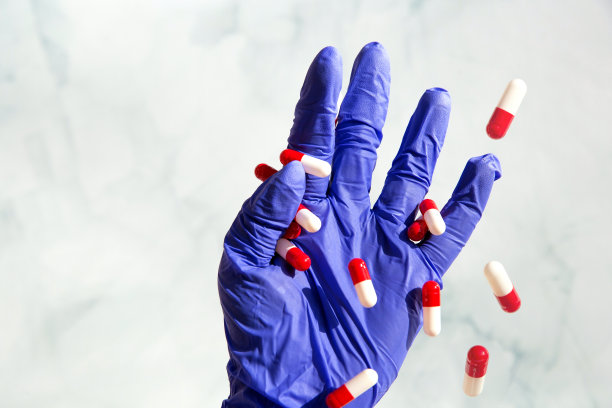 一只戴着蓝色乳胶手套的手抓着满手的药品，维生素胶囊，药品，药物。健康、经营理念图片下载