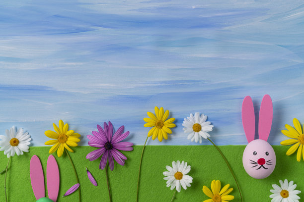 在绿色的毛毡上画有复活节兔子的脸和水彩蓝色的天空图片下载