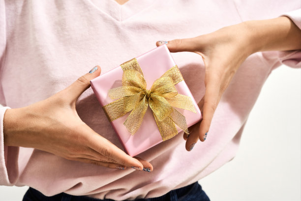 送给妈妈的礼物。一名妇女拿着带金色蝴蝶结的包装好的小礼盒，图片下载