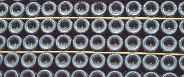 封闭的旧酒瓶底部覆盖着灰尘，黑暗的酒窖里有旧酒瓶的红酒，横幅图片下载