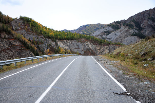 两条车道的柏油路穿过一个狭窄的山谷。图片下载