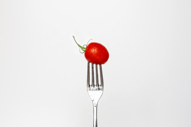 一个新鲜的樱桃番茄在叉子孤立的白色背景的照片，系列的一部分。图片下载