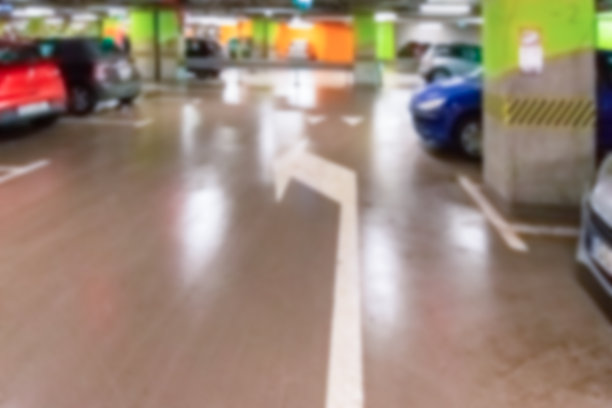 车库汽车模糊。车位在城市地下车库。空道路沥青背景软焦点。停车场用混凝土骨架。图片下载