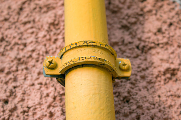 一根带有耦合器的黄色煤气管道沿着多层建筑的立面运行。这房子接通了家用煤气。图片下载