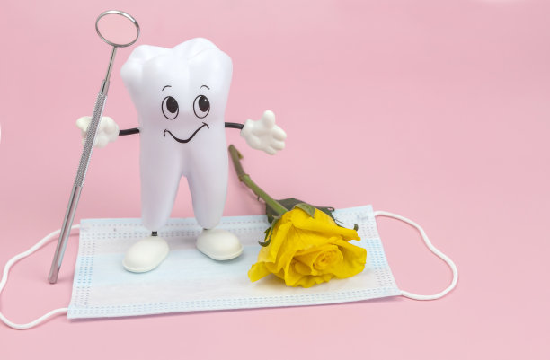 卡通模型的牙齿与牙科镜，玫瑰和一个保护面罩在粉红色的背景图片下载