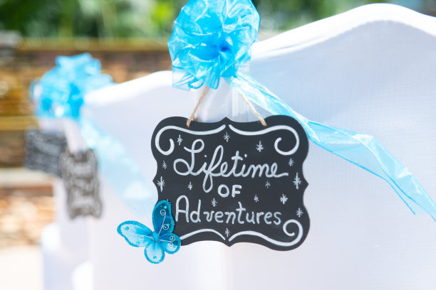 “一生的冒险”的婚礼标志与白色的字母在黑板上挂在白色的椅子图片下载