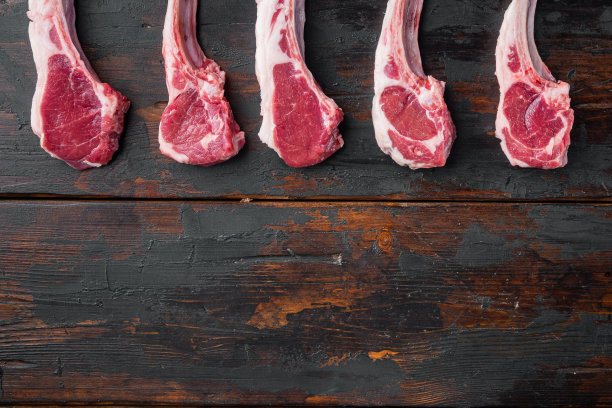 新鲜的羔羊肉片。有机肉排，在旧的深色木桌子的背景，俯视图平躺，与copyspace和文本空间素材图片