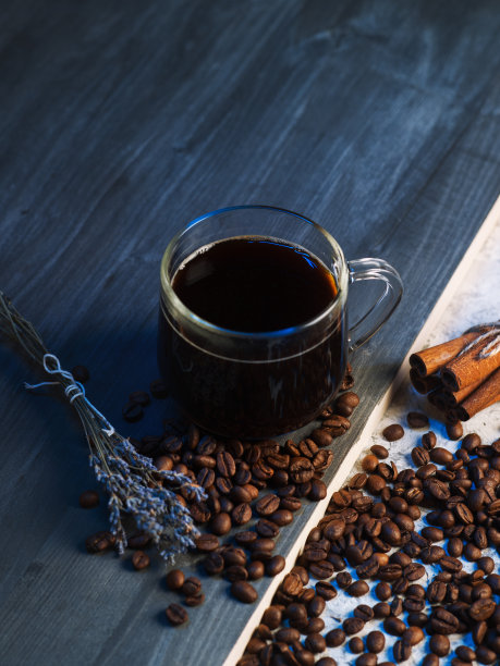 深色木桌上放着一杯浓缩咖啡。撒上烤咖啡豆，一小枝薰衣草和肉桂。俯视图垂直照片图片下载