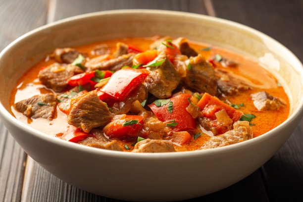 传统的匈牙利红辣椒与火鸡，甜椒，胡萝卜，洋葱，红辣椒和酸奶油在深色的木制背景碗图片下载