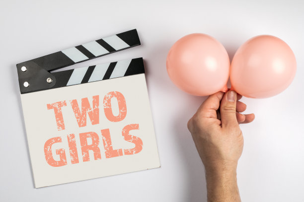 两个女孩。生日和超声检查的概念。电影拍手和白色背景上的粉色气球图片下载