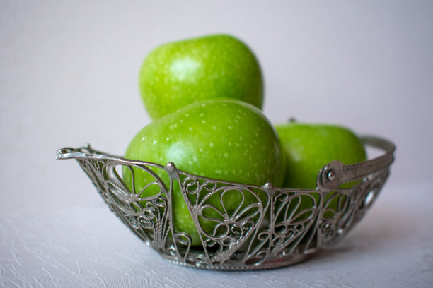 几个熟透的青苹果放在一个陈年的篮子里图片下载