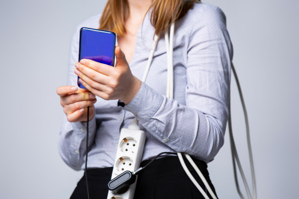 裁剪的照片，年轻的智能手机用户。数字移动通信技术的概念。灰色背景中，手持智能手机的女性，手持手机充电线的女性图片下载