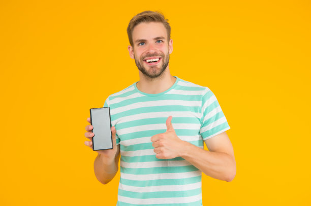 我们测试过的最好的手机。快乐的人对手机竖起大拇指。帅哥拿着手机。现代生活。移动电话通信。新技术。3 g。4 g。智能手机比以往更好图片下载