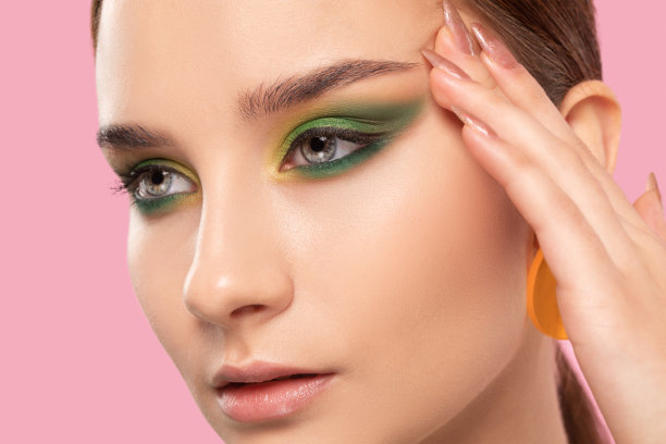 黑发女孩，漂亮的绿色妆容，干净的皮肤，圆圆的耳环。化妆的概念。图片下载