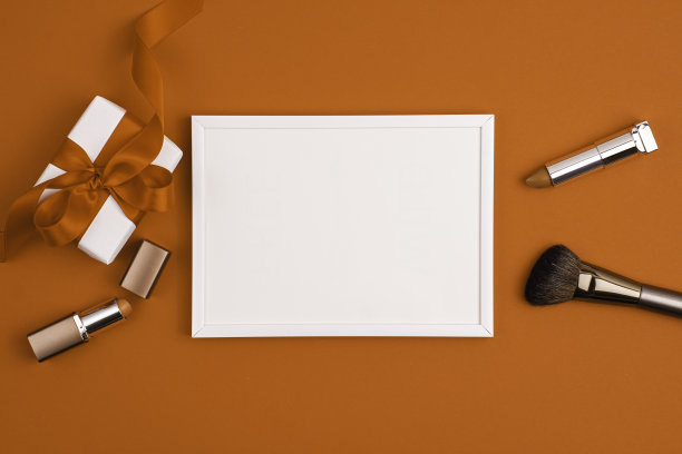 模型白色框架白色礼物与红色蝴蝶结，化妆刷和口红上充满活力的橙色图片下载