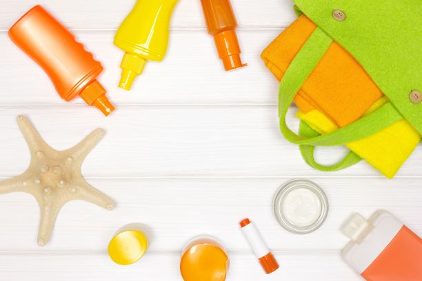 面部和身体防晒化妆品与毛巾在白色木板。防晒化妆品。平面框架。夏季海上度假概念图片下载