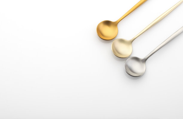 白色桌子上放着不同颜色的金属汤匙，银制餐具，复印空间图片下载