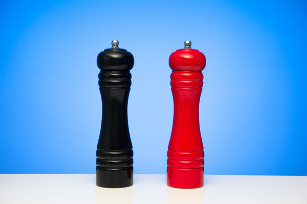 木制黑胡椒研磨机和红盐研磨机孤立在蓝色背景上图片下载