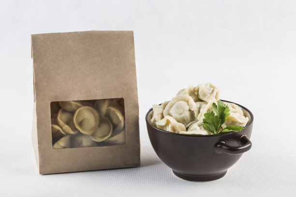 饺子用环保纸包着送，一碗饺子放在白色的背景上，与世隔绝。图片下载