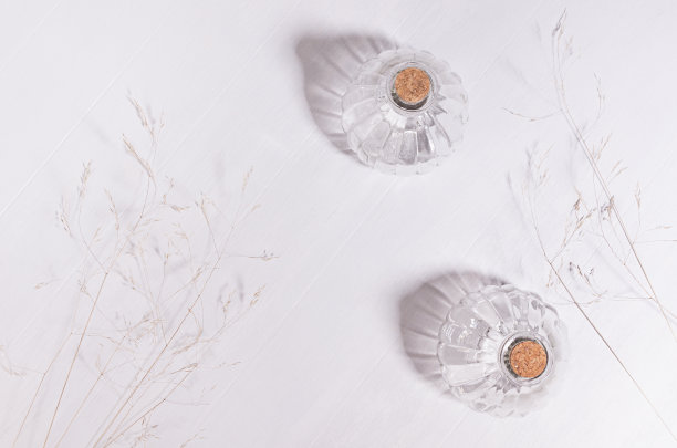 现代宁静的背景与米黄色干草，透明玻璃花瓶在早晨的阳光，阴影在白色木板，俯视图，拷贝空间。图片下载