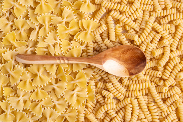 一个木勺放在生意大利面和意大利细面条上。图片下载