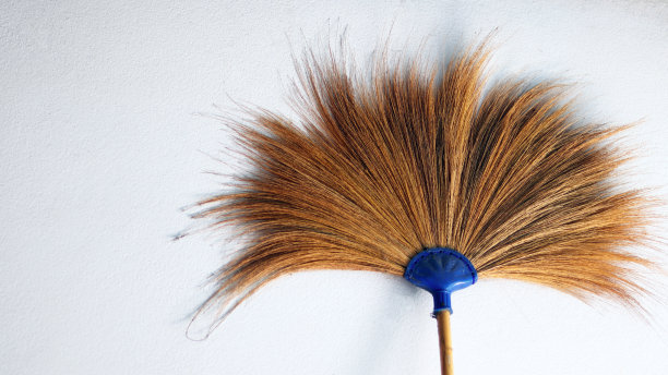 用干草叶和竹子制成的扫帚用于清洁肮脏的地板，用于室外拖地的清洁工工具，隔离在白色混凝土墙壁上，家政设备概念复制空间。图片下载