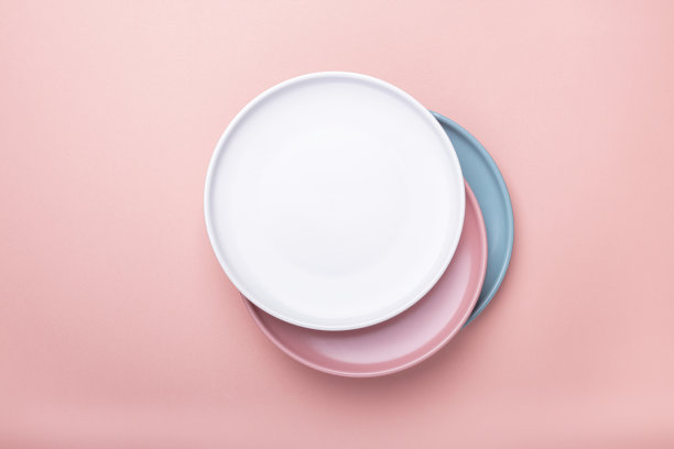 粉红色背景上的粉红色、白色和绿色空盘子。前视图。图片下载