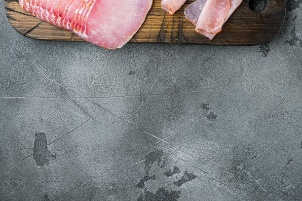 火腿片，在灰色的石头背景上，平铺俯视图，与文本复制空间图片下载