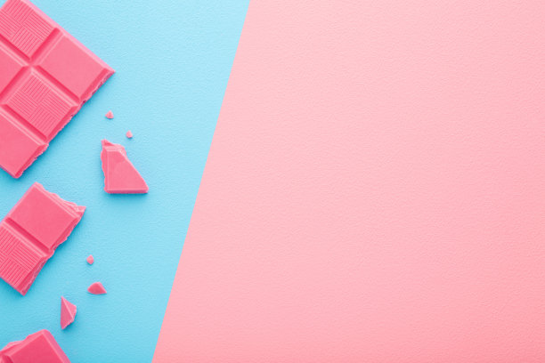 碎巧克力在浅粉蓝色的桌子背景上。柔和的颜色。甜的零食。特写镜头。文本的空位置。自顶向下的观点。双方。图片下载
