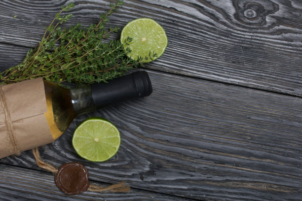 酒精瓶。包裹在纸上。附近的百里香和酸橙。松木板。图片下载