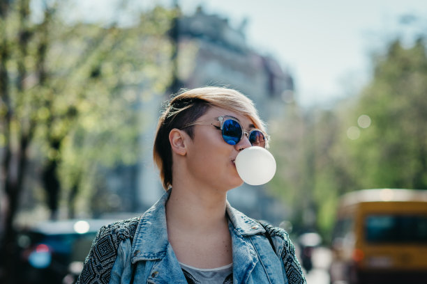 年轻的短发女人在吹泡泡糖图片下载