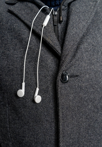 白色耳机上的背景一名男子的外套近距离。图片下载