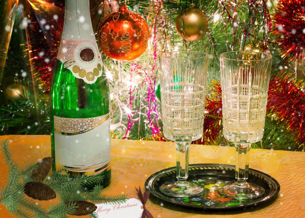 圣诞假期，酒和杯子在圣诞树旁。“n图片下载