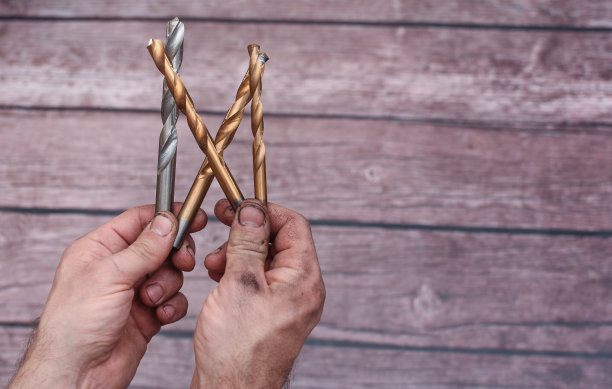 干活弄脏了，男人们的手拿着金属钻头图片下载