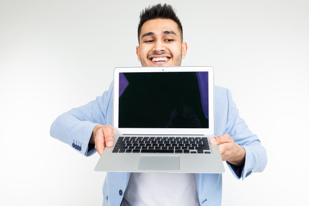 微笑的年轻褐发男子愉快地拿着一个空白的笔记本电脑插入一个网站页面的白色背景图片下载